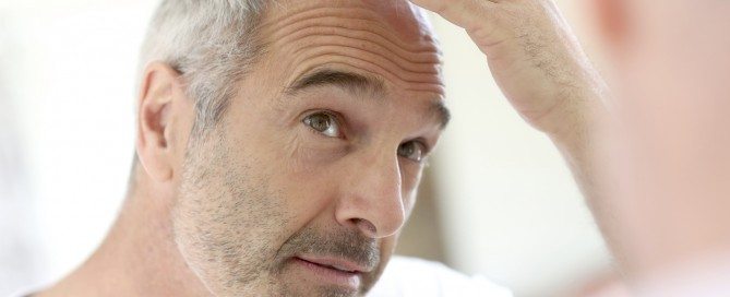 Mature man looking at his thinning hair