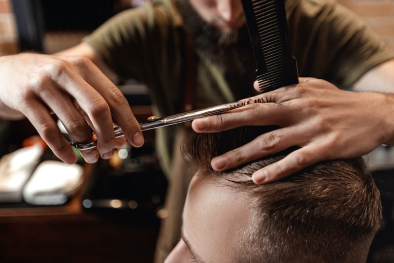 Stylist Giving Man A Haircut In Barbershop